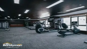 Modern indoor gym with treadmills-exercise bikes-and large windows letting in natural light.