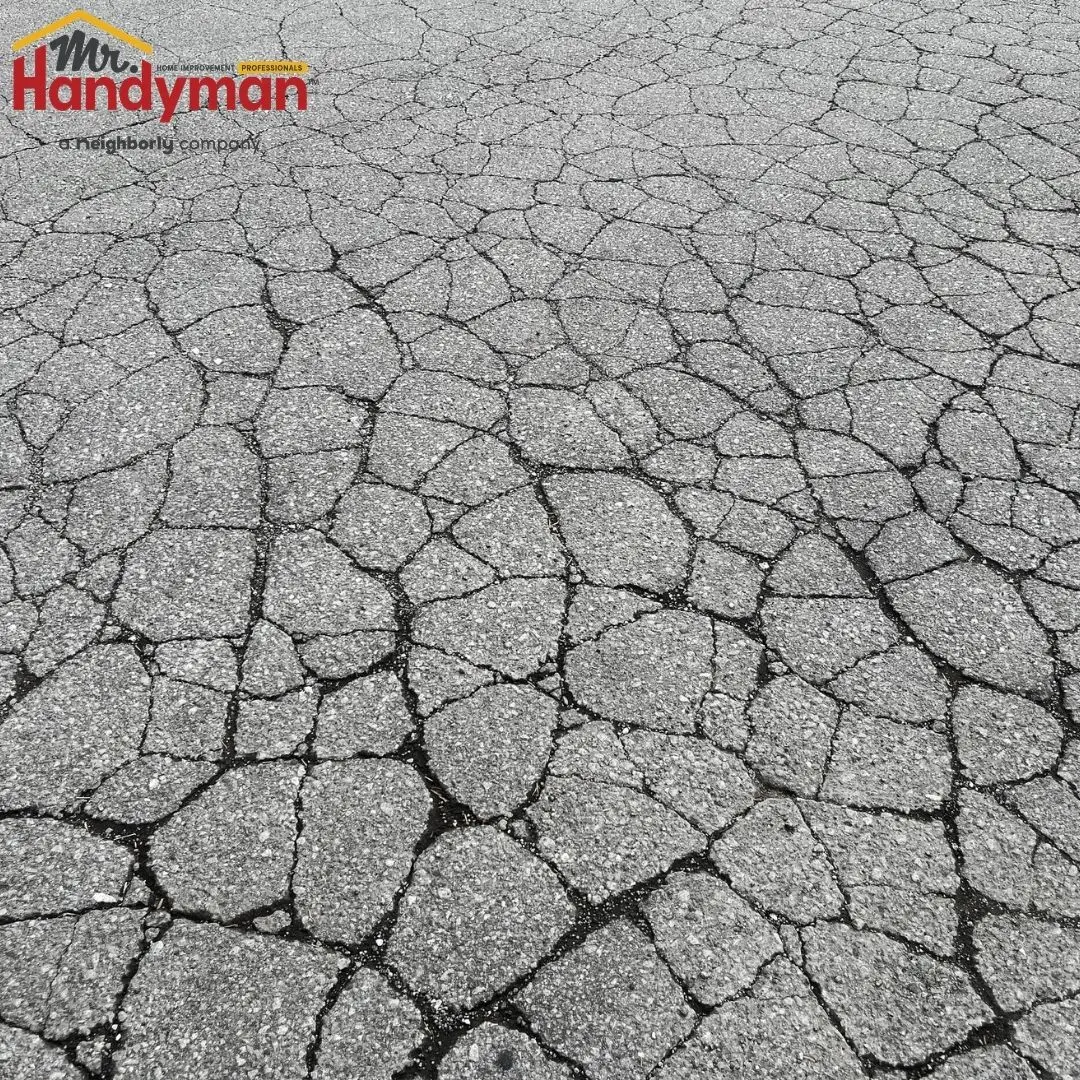 A close up view of gray asphalt pavement covered in a dense network of cracks.