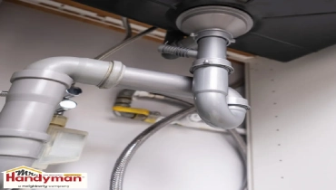 Plumber inspecting basement sump pump after spring storm flooding in South Bend Indiana