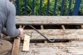 Removing wood rot deck planks.