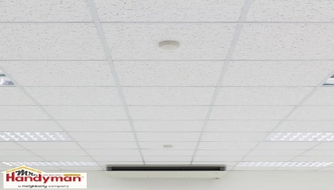 Handyman replacing stained ceiling tiles in a commercial space in West Nashville Tennessee