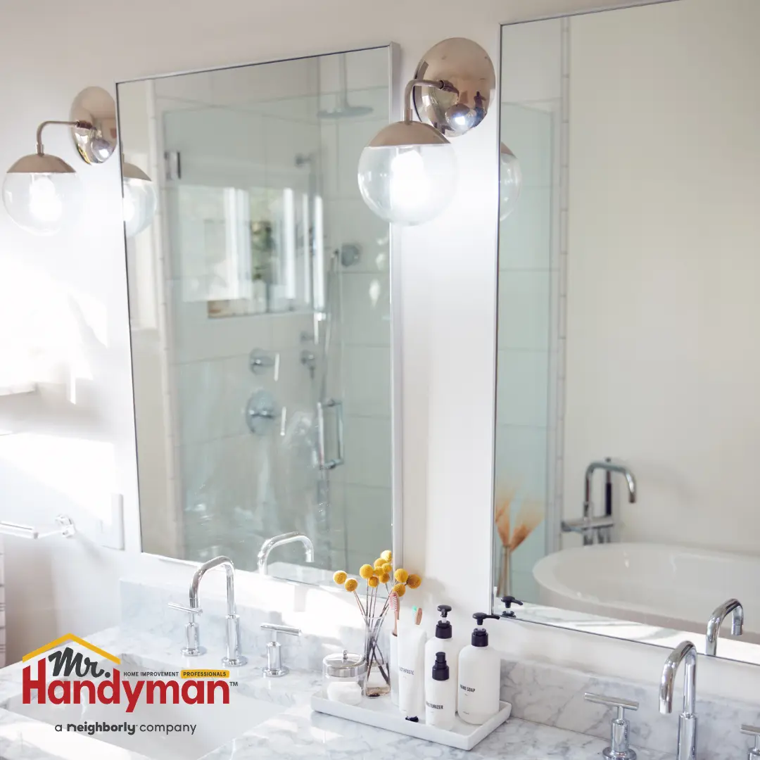 A modern bathroom featuring a large wall mirror, sleek chrome fixtures, and a countertop arrangement of toiletries.