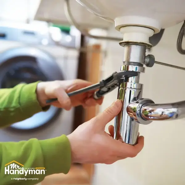 Mr. Handyman technician inspecting outdoor spigot and plumbing in Easton PA home during spring