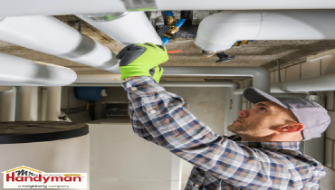 Technician in inspecting or repairing white pipes in a basement or utility room.