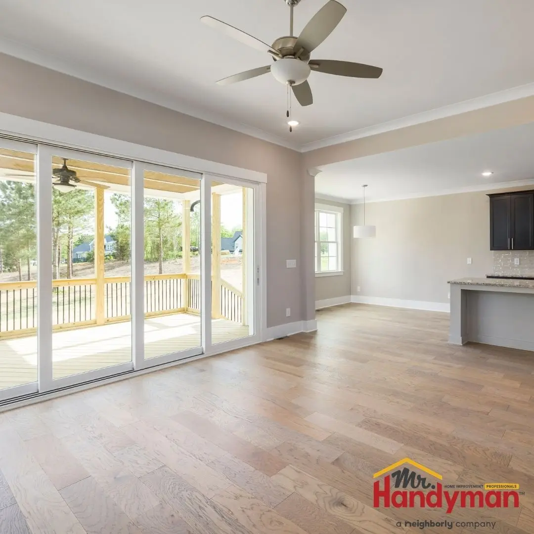 A spacious living area featuring light hardwood flooring and large sliding glass doors.