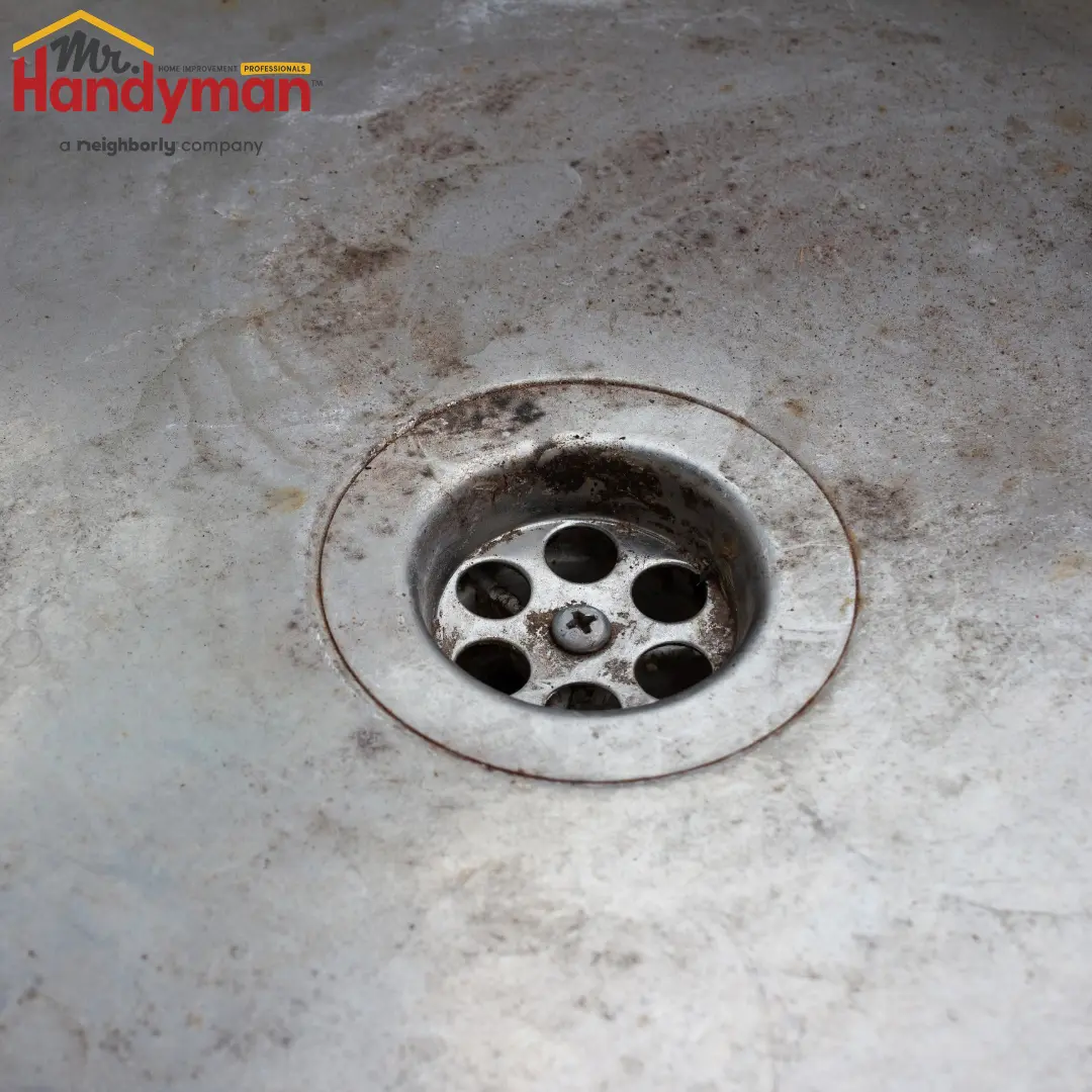 A dirty sink with a rusty drain.