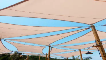Handyman installing a shade sail over a backyard patio at a Cedar Hill, TX home