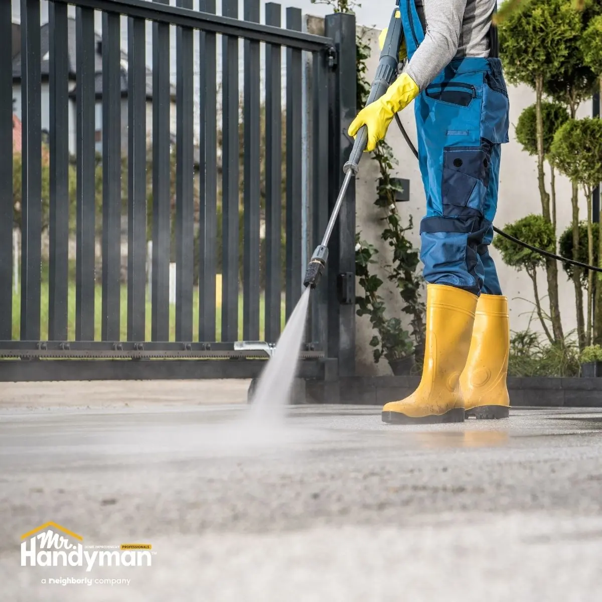 Worker pressure-washing driveway.