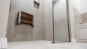 A modern walk-in shower with large gray wall tiles.