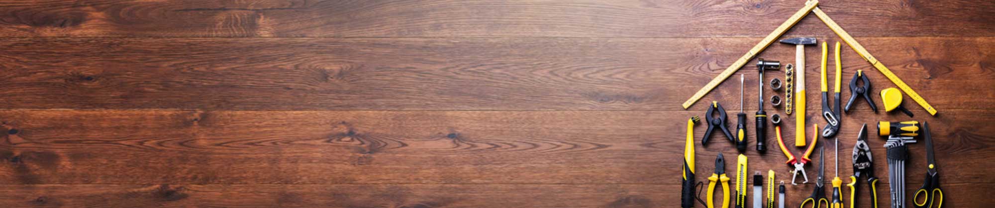 Tools laid out in the shape of a house on a wooden background.