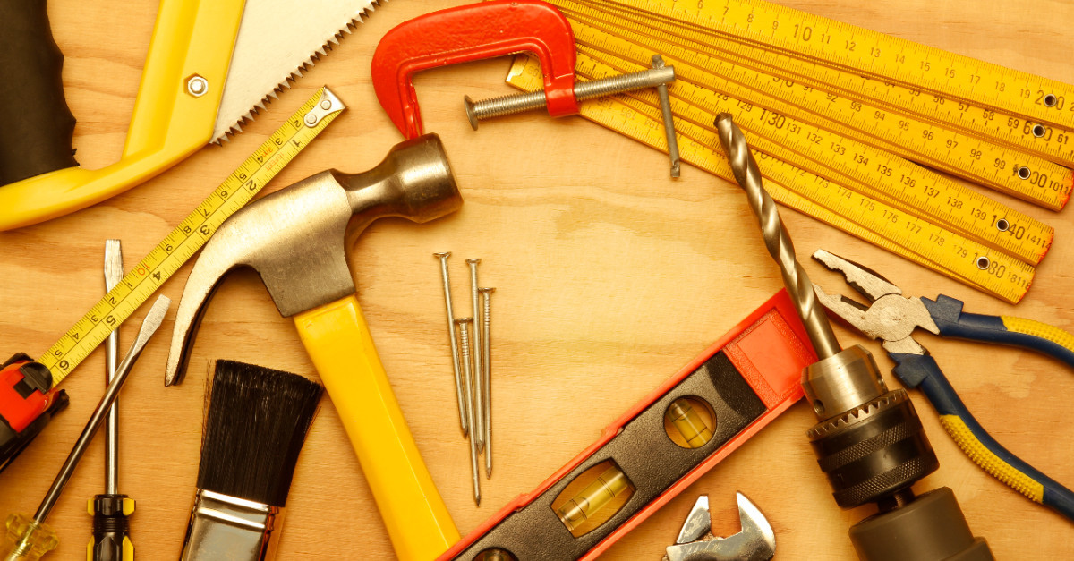 A collection of tools that could be used by a handyman in Stoughton, MA, including a hammer, drill, set of rulers, a level, screwdrivers and a tape measure.