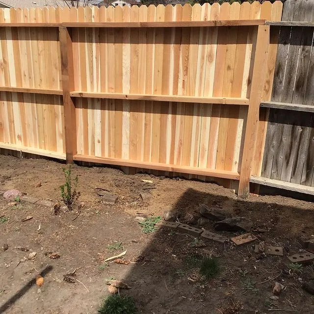 A wooden, residential fence with a new section that has been added by Mr. Handyman during an appointment for fence repairs.