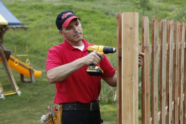 A handyman from Mr. Handyman drilling a new picket onto a fence during an appointment for fence repair in Quincy, MA.