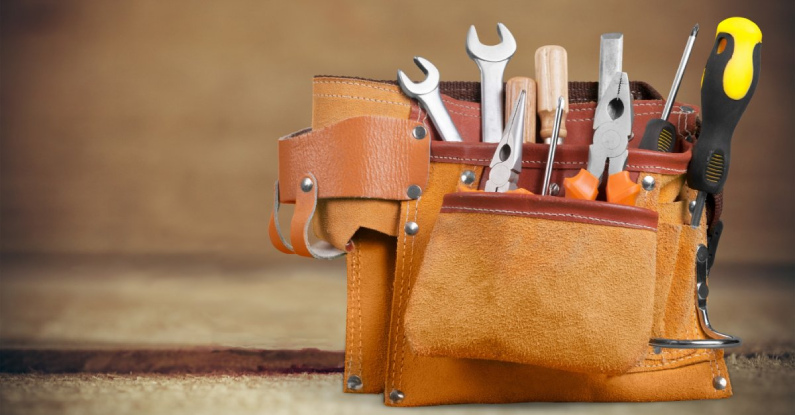A tool belt with several tools that could be used by a handyman in Cedar Hills, UT, including two pairs of pliers, two wrenches, and two screwdrivers.