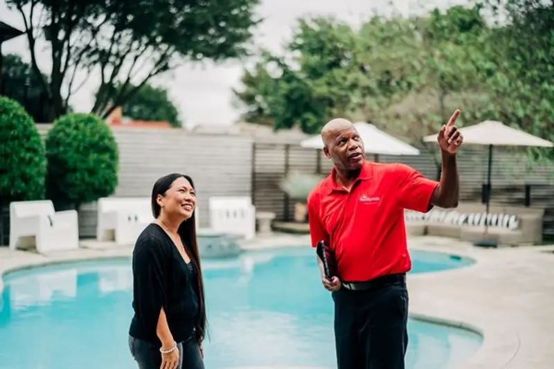 Handyman standing near pool with customer