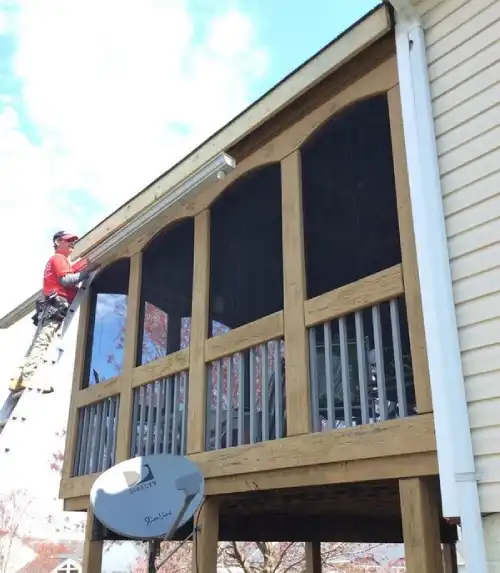 Mr. Handyman technician installing a gutter on a three-season porch in Dale City, Virginia.