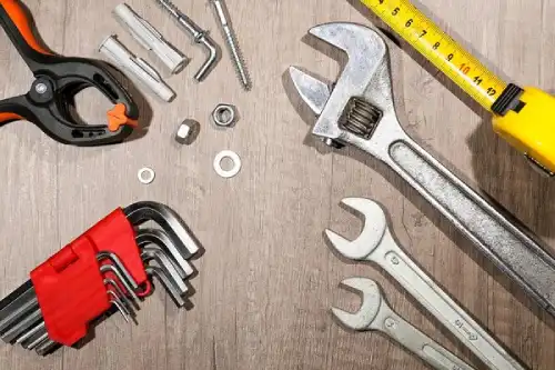 Tools like wrenches, tape measure, pliers, and hex L-keys on a wood surface.