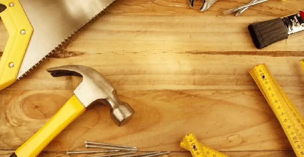 Several tools that would commonly be used by a handyman in West Chester, OH, including a hand saw, hammer, rulers, and several nails.