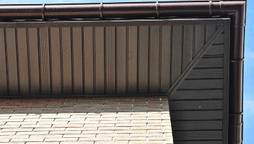 The soffits of a residential roofline that has received soffit service viewed from the ground looking up toward the roof.