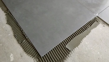 Large gray tiles being laid overtop of grout during a new tile installation in Colorado Springs.