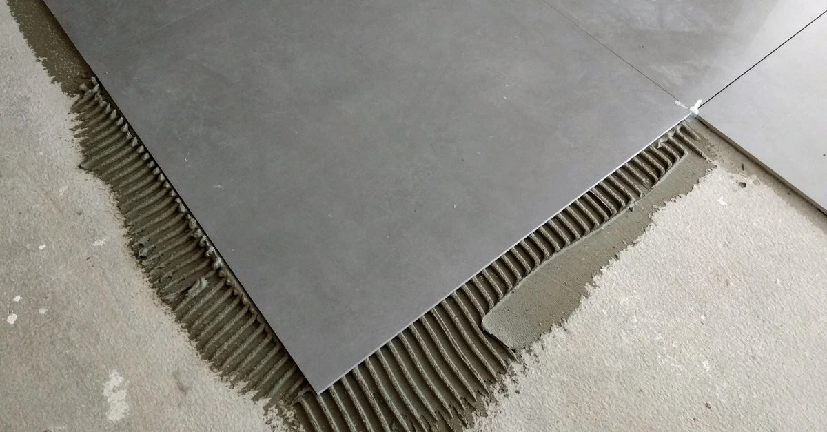 Large gray tiles being laid overtop of grout during a new tile installation in Colorado Springs.