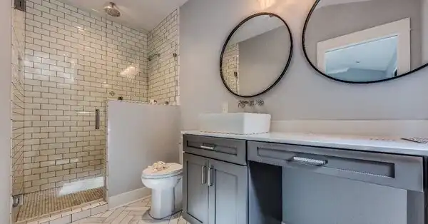 A modern bathroom with subway tile, circular mirrors, a low clearance cabinet and other features that are popular in Cincinnati bathroom remodel projects.