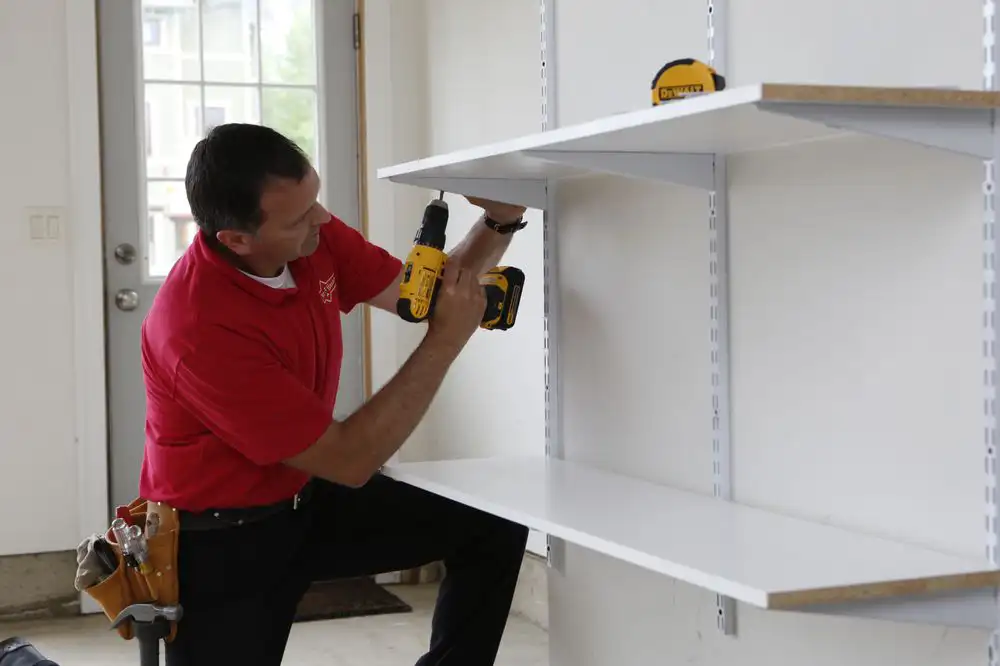 A commercial handyman in Cincinnati using a drill to set up a shelving unit inside of a business.