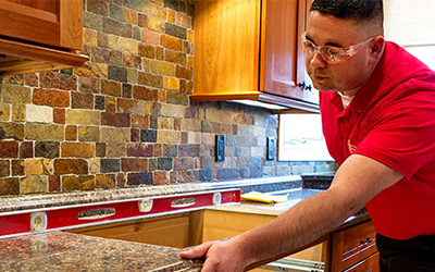 A handyman from Mr. Handyman installing a new countertop on top of kitchen cupboards during a kitchen remodel in Frisco, TX.