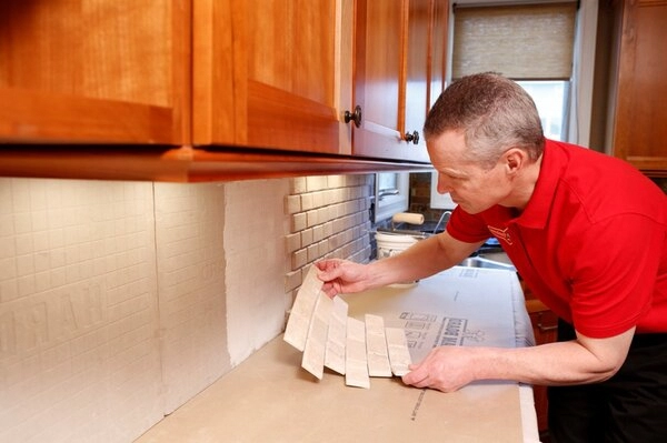 Mr. Handyman technician installing tile backsplash during kitchen remodeling in Brighton, CO