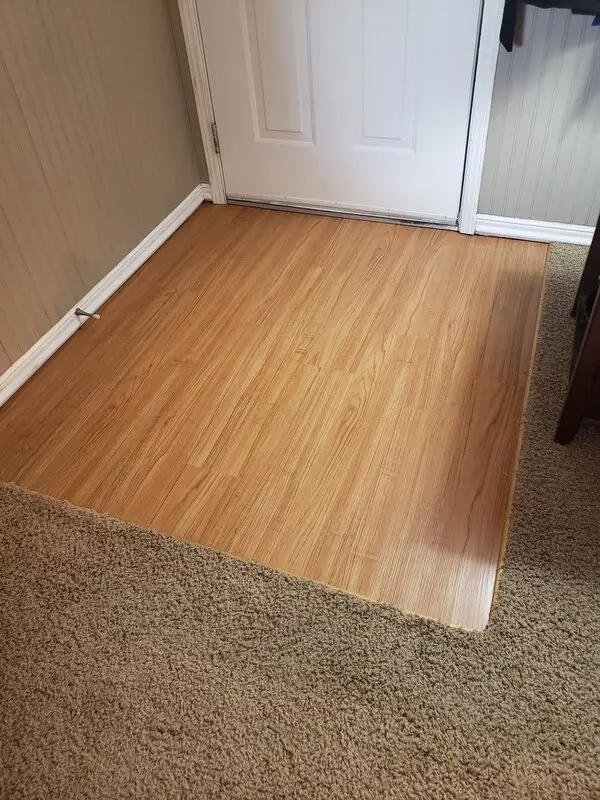 A carpeted floor with a section of hardwood near a door after receiving flooring repairs in Vancouver, WA.