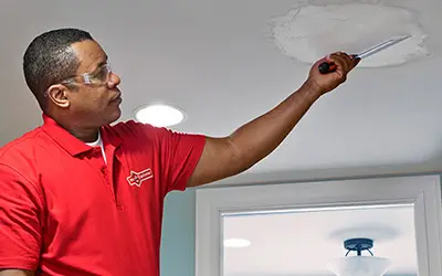 A Mr. Handyman professional repairing a piece of ceiling drywall