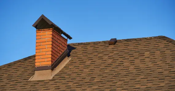 The top of a sloped, residential roof where a brick chimney is installed and has been kept in good condition with services for chimney repair in Knoxville.