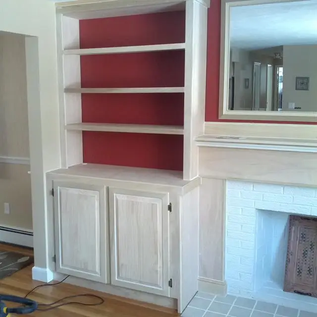 Custom, built-in cabinets and shelves next to a fireplace in a home that has received services for customer carpentry in Norfolk, MA.