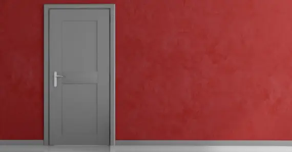 A closed, gray door installed on a red wall on the inside of a home in Tulsa, Oklahoma