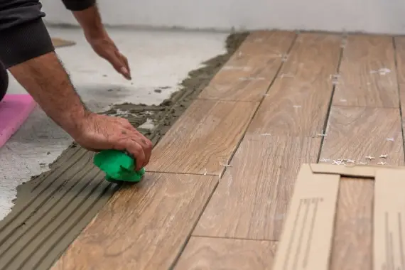 A handyman meticulously installing hardwood flooring tiles.