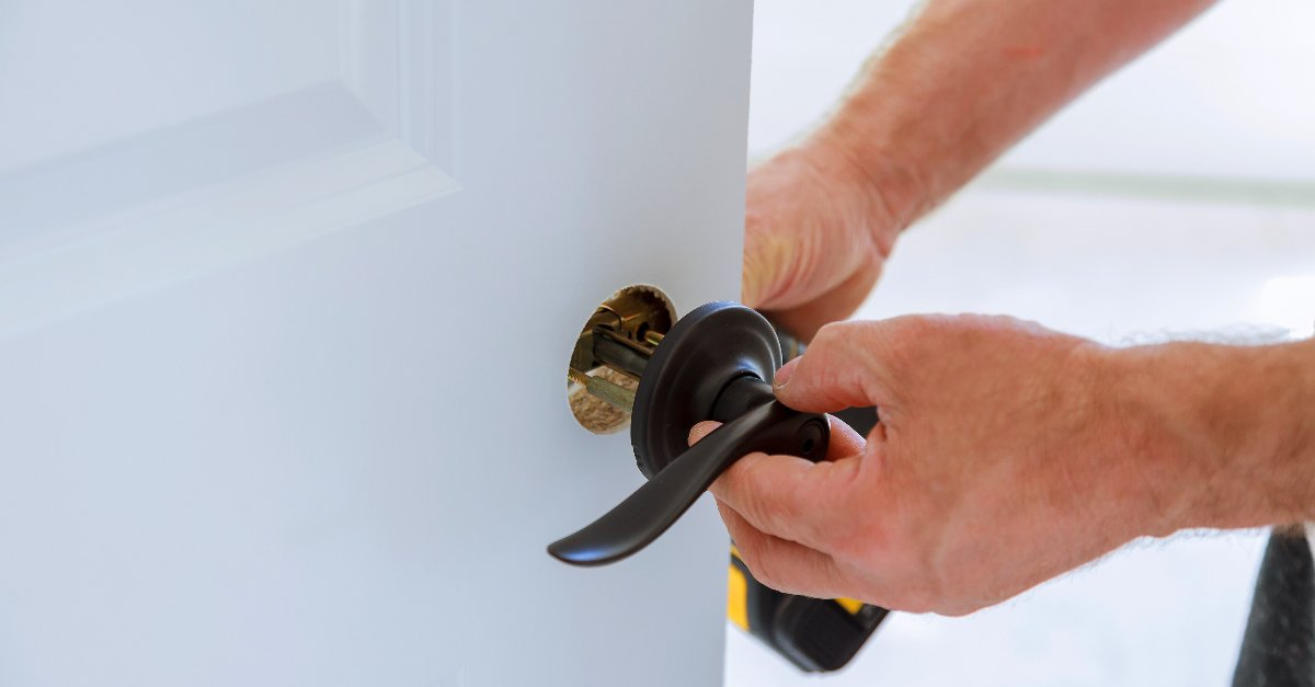 A handyman replacing the doorknob on a door during an appointment for door repair in Fairfield.