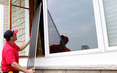 Mr. Handyman professional installing a new window and window screen