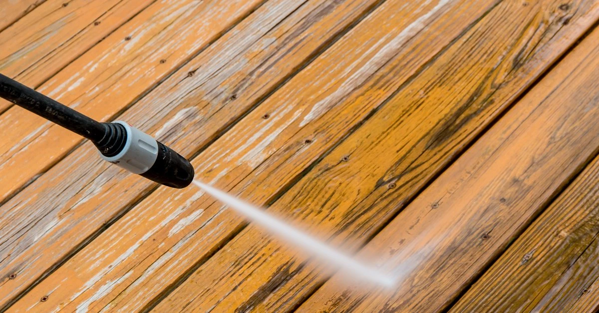A pressure washing nozzle shooting a jet of water at a wooden deck during an appointment for pressure washing in Knoxville, TN.