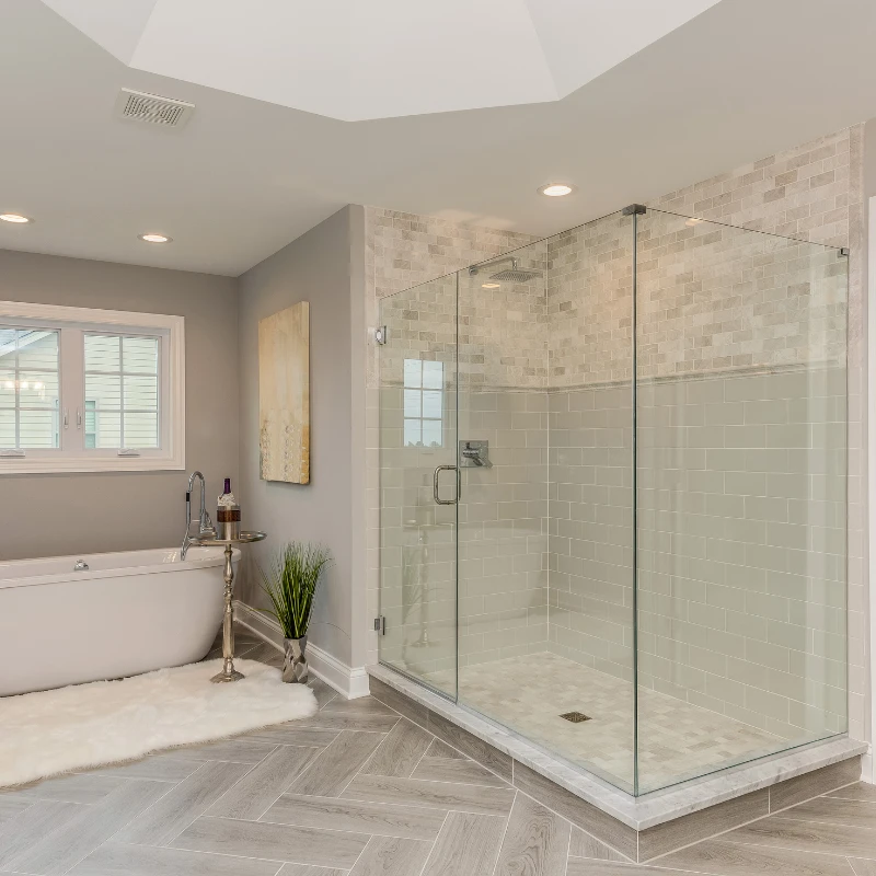 A residential bathroom featuring a glass shower enclosure, and a standalone tub with new flooring and shower tile installed during a bathroom remodel.
