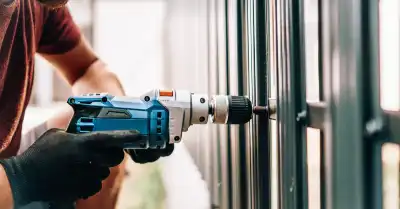 Person using a drill to build a metal fence.