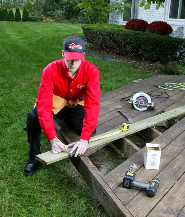 Mr. Handyman technician measuring plank of mood for deck improvement