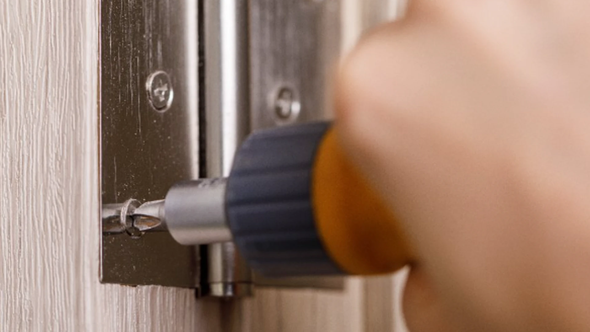 A handyman using a screwdriver to attach new hinges to an interior door frame during an appointment for interior door repair in Frisco, TX.