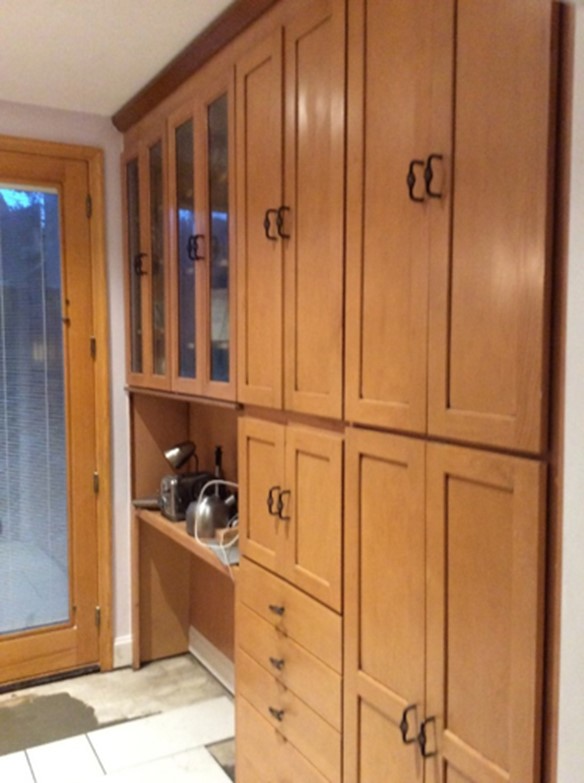 A wall of kitchen cabinets that have been modified with handles, and with the doors removed from some sections, in order to increase accessibility for aging in place.