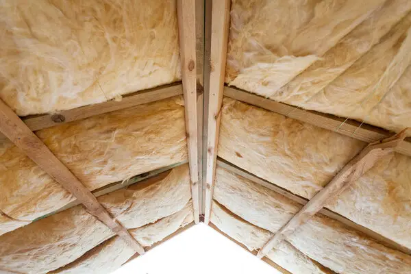 The ceiling of an attic with exposed beams after the empty gaps have been filled with attic insulation in Flower Mound, TX.