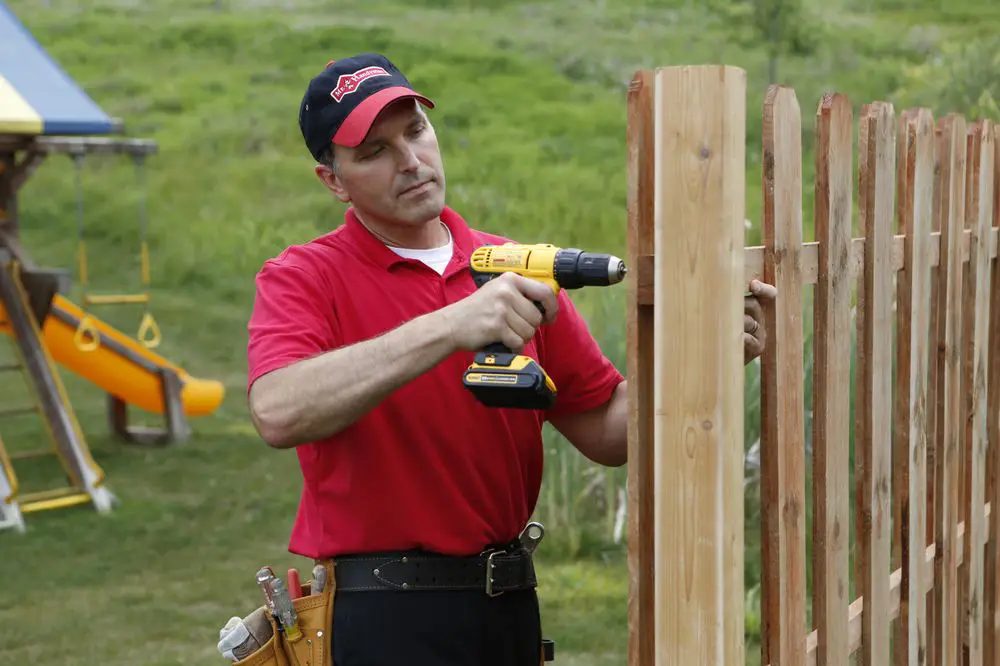 A Colorado Springs carpenter from Mr. Handyman fixing a fence by replacing one of the pickets.
