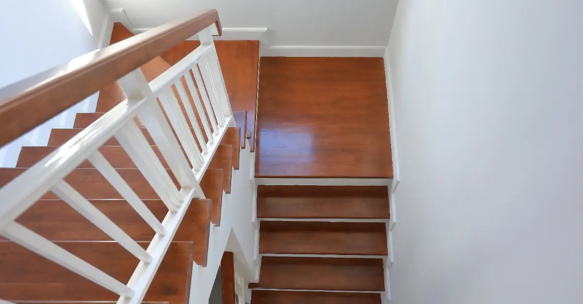 A top-down view of a residential staircase with a landing halfway down where the staircase flips back around as it continues downward.