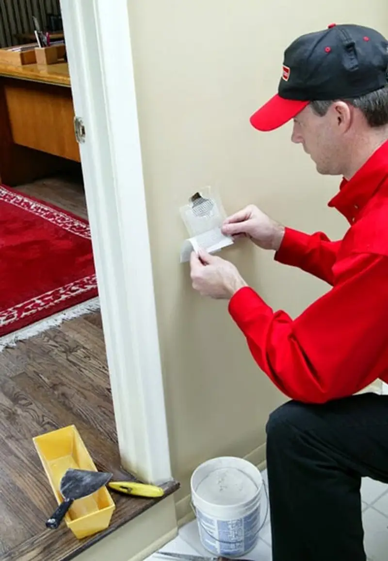 A Stratmoor handyman repairing drywall using a mesh patch.