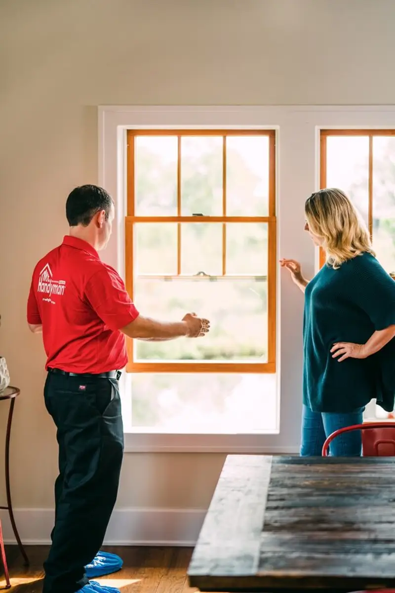 Mr. Handyman technician inspecting newly repaired window frame with homeowner in Sundance.