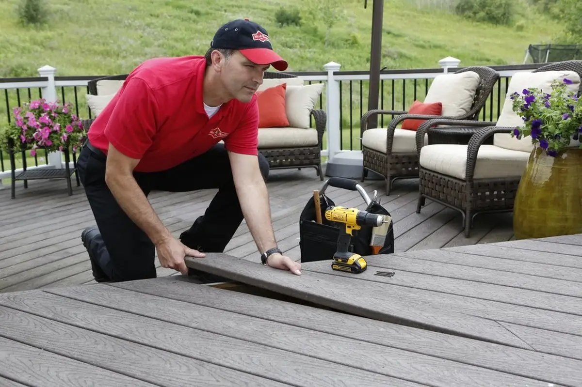 A Mr. Handyman technician installing a new deck board in a deck during an appointment for Colorado Springs carpentry service.