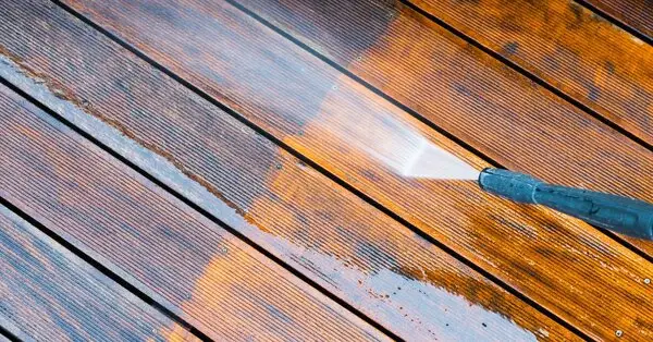 Wooden deck boards as a layer of dirt is cleaned away by a jet of water during an appointment for power washing in Charleston, SC.